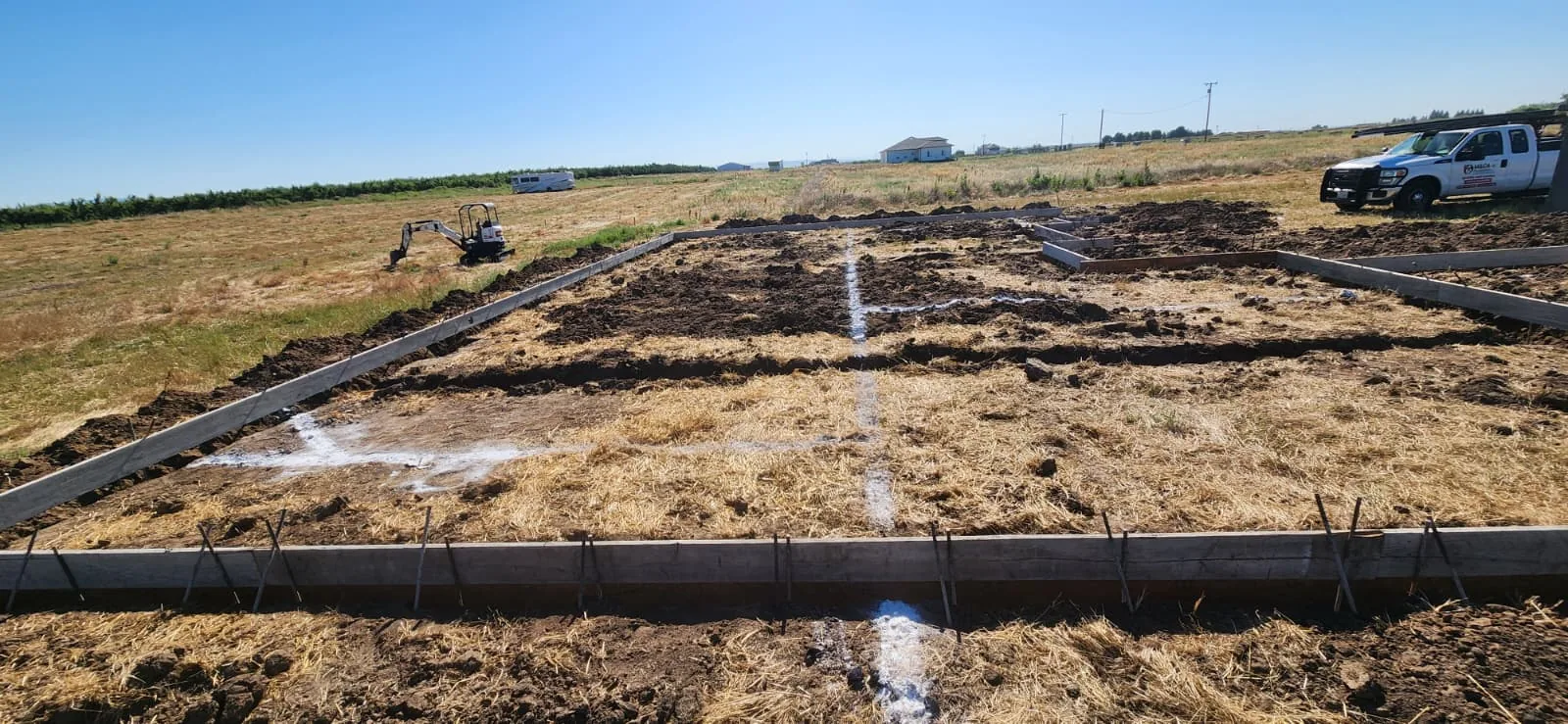 Underground pipe installation — excavated trench with PVC sewer lines, below-grade drainage system, soil and gravel backfill, construction site